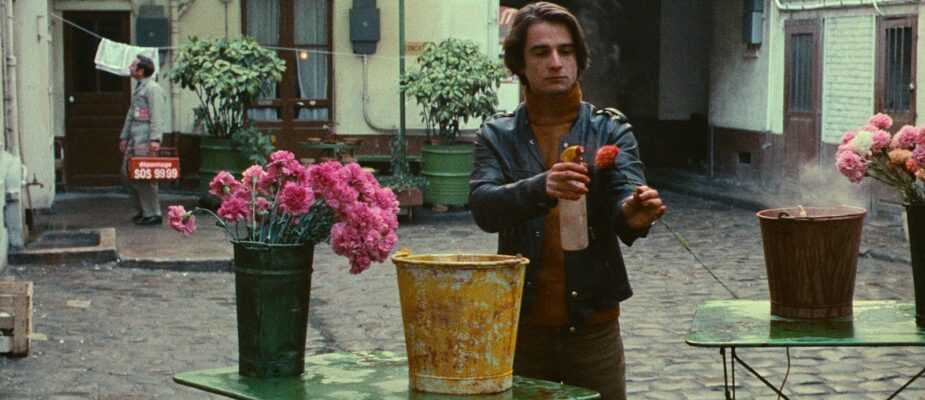 A film still from Bed and Board with Antoine Doinel spraying a flower with water.