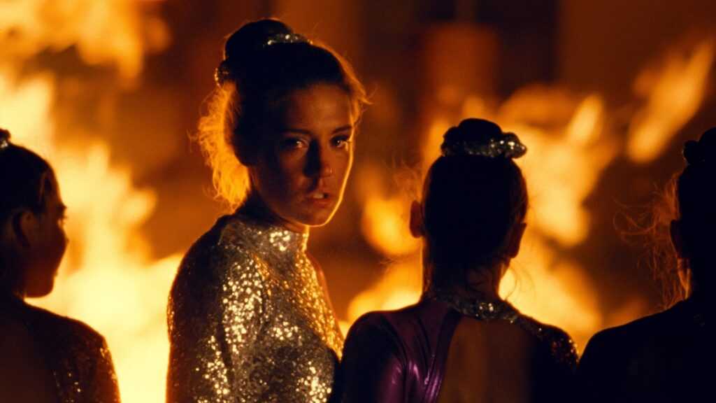 A film still from the The Five Devils of Adèle Exarchopoulos in a gymnastics uniform with flames behind her.