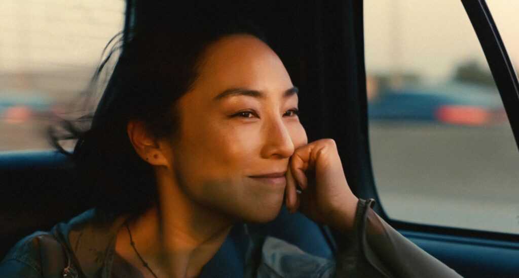 A film still from Past Lives with a closeup of Greta Lee looking out a car window.