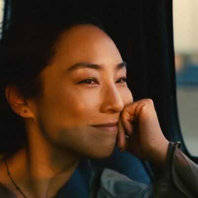 A film still from Past Lives with a closeup of Greta Lee looking out a car window.