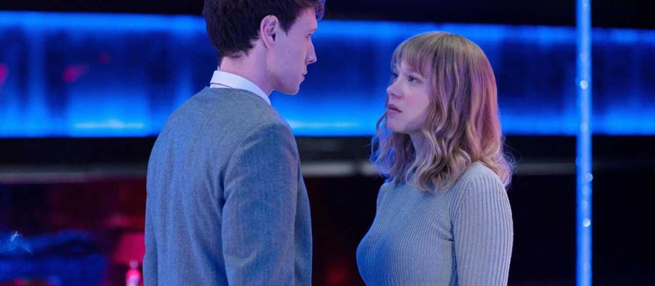 THE BEAST Photo1 © Carole Bethuel. A man (George MacKay) and woman (Léa Seydoux) stand close together in the middle of a nightclub, staring at each other.